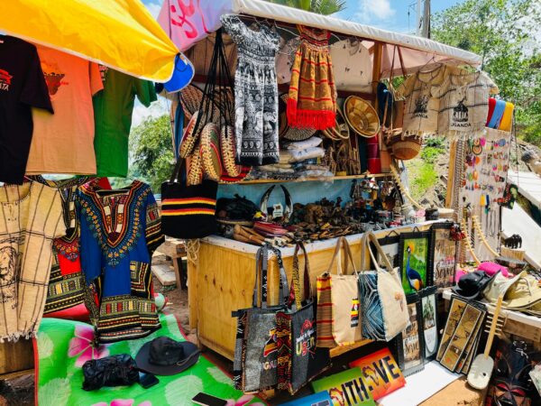 Colorful African market stall displaying traditional clothing, bags, and crafts.