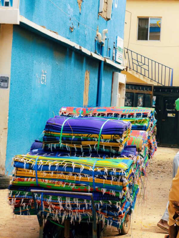 Vibrant fabric bundles stacked outside a shop in Kano, Nigeria.